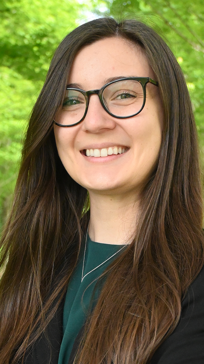 Headshot of a woman wearing glasses and a black jacket over a green blouse.