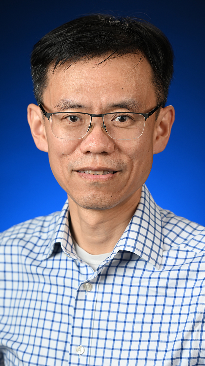 Headshot of a man wearing glasses and a checked shirt.
