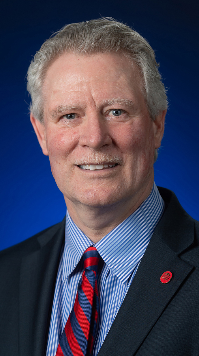 Headshot of a man wearing a blue suit.
