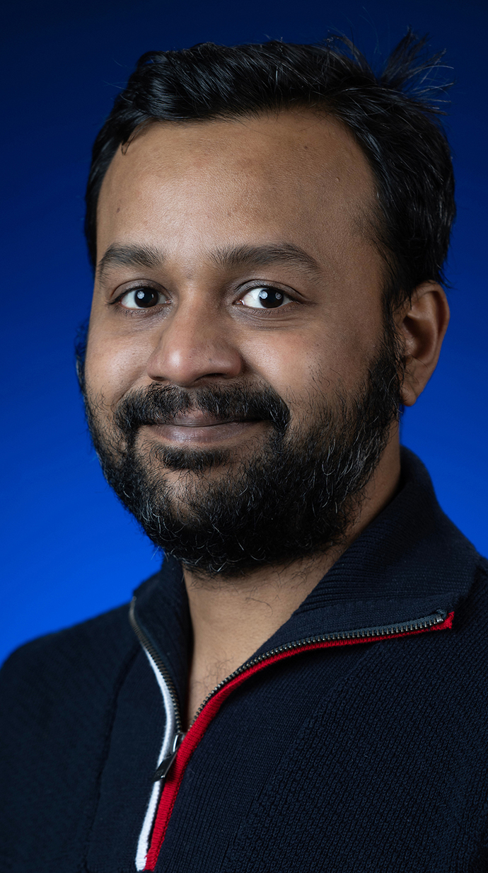 Headshot of a man wearing a blue-pull-over shirt.