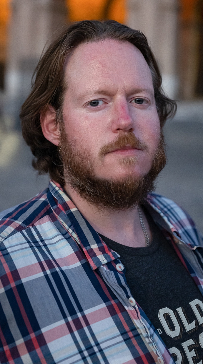 Headshot of a man wearing a plaid shirt.