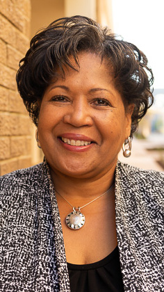 Headshot of a woman wearing a black-and-white jacket over a black blouse.