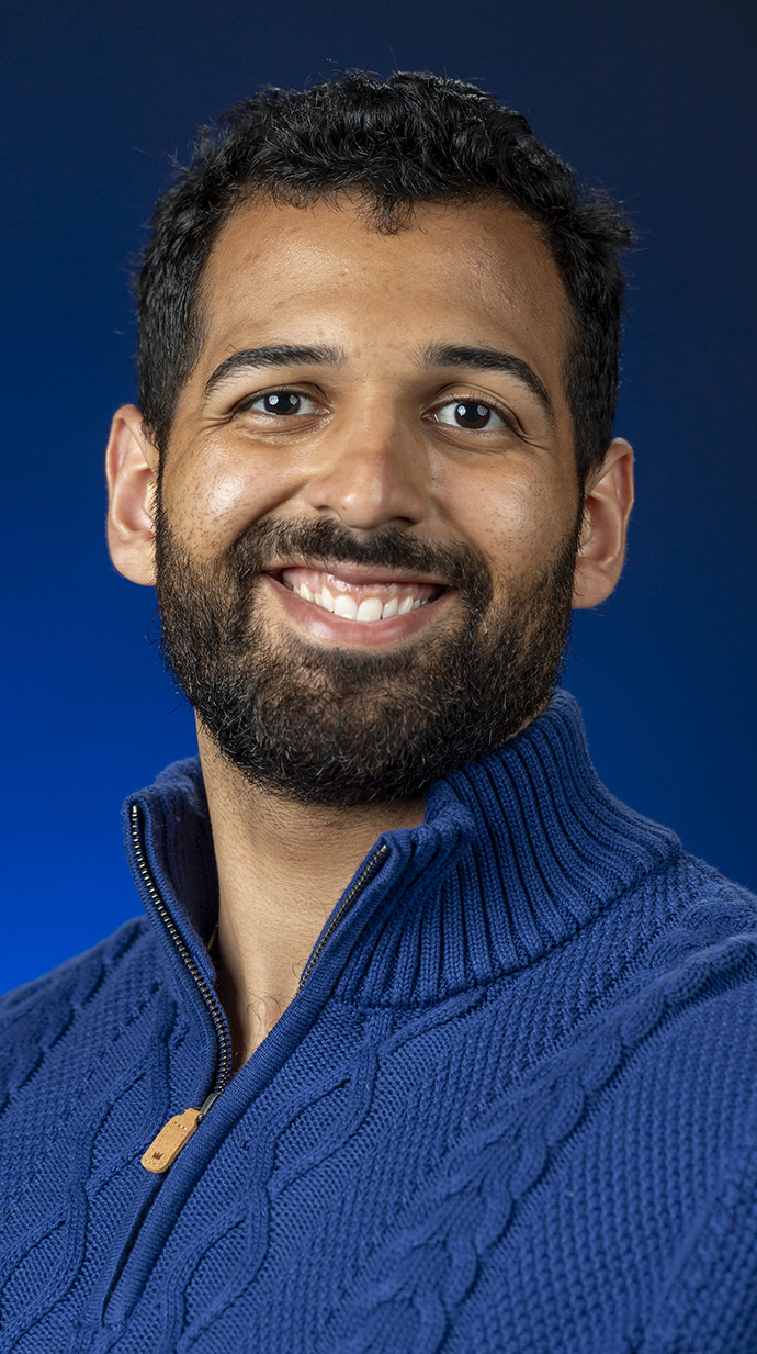 Headshot of a young man wearing a blue zippered sweater.