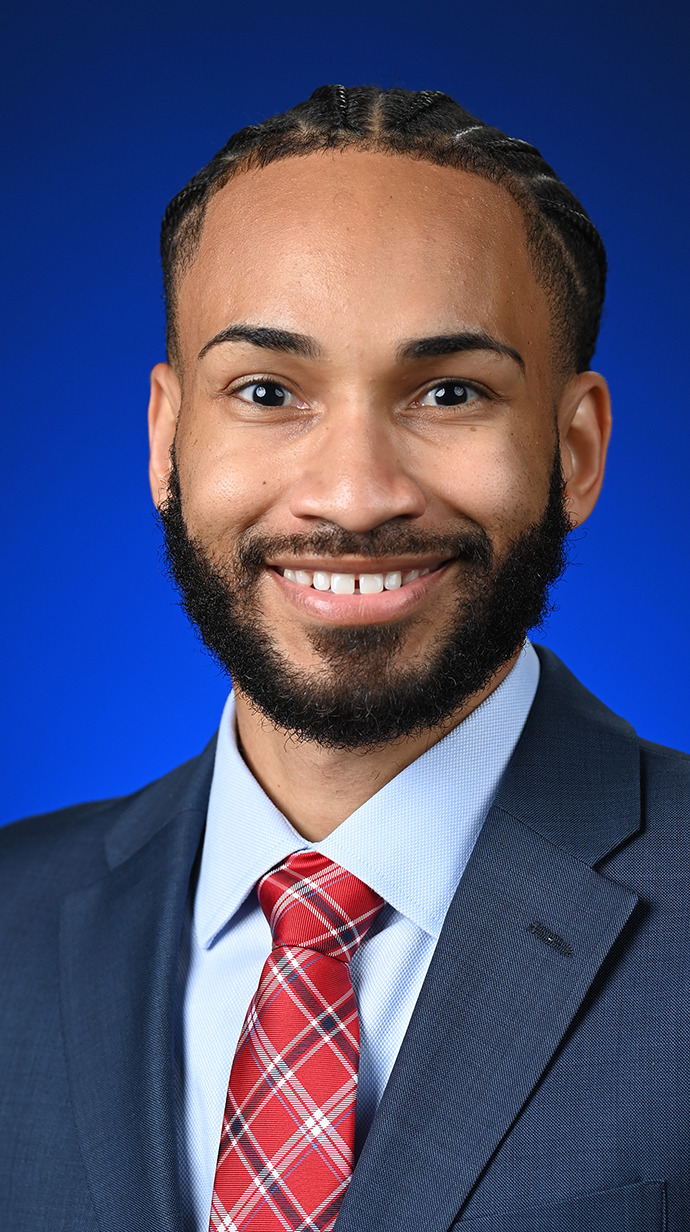 Headshot of a man wearing a dark blue suit with a red tie.