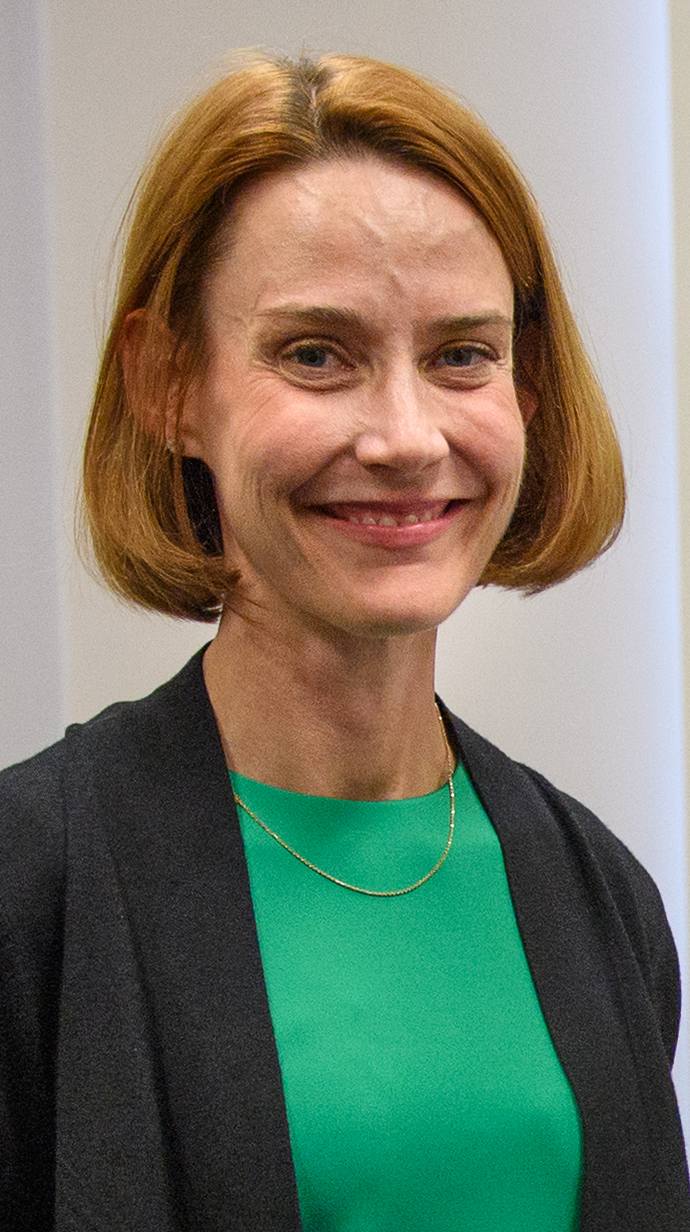 Headshot of a woman wearing a black sweater over a green blouse.