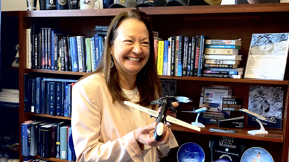 A woman holds a small replica of a drone in an office.