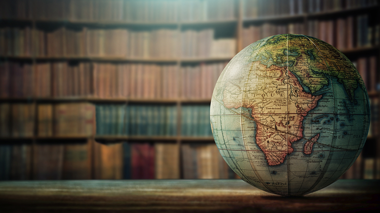 A globe in front of large bookcases is turned to show Africa.