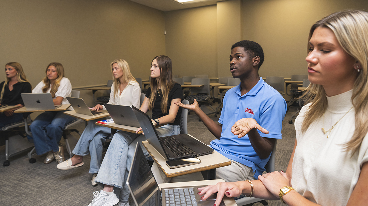 A group of young people sit in a college classroom.