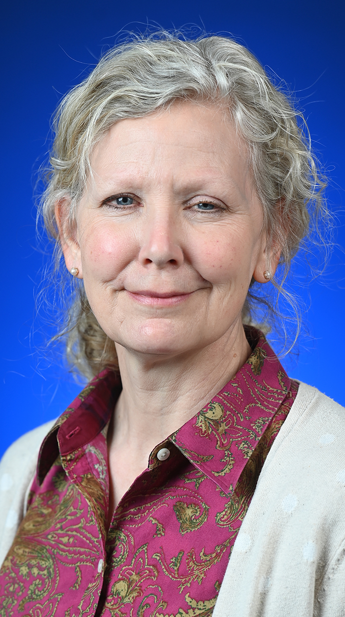 Headshot of a woman wearing a white sweater over a red print shirt.