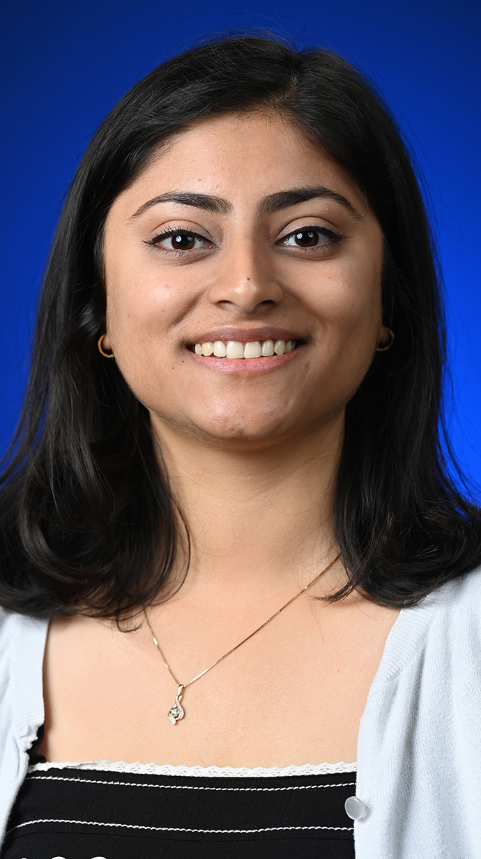Headshot of a young woman wearing a white sweater over a black blouse.