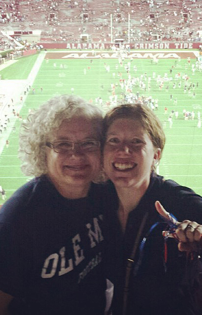 Two women take a selfie at a football stadium.