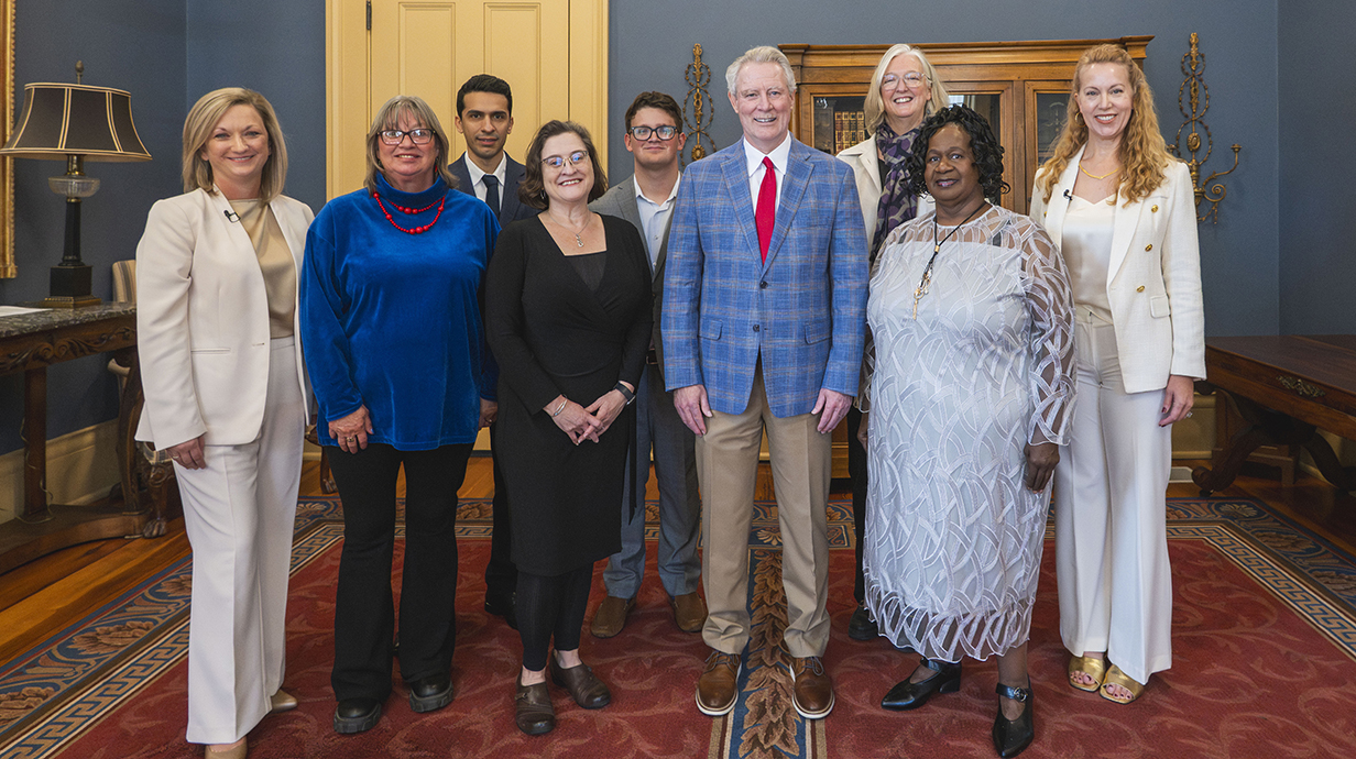 A group of people stand in a line in an ornate office.