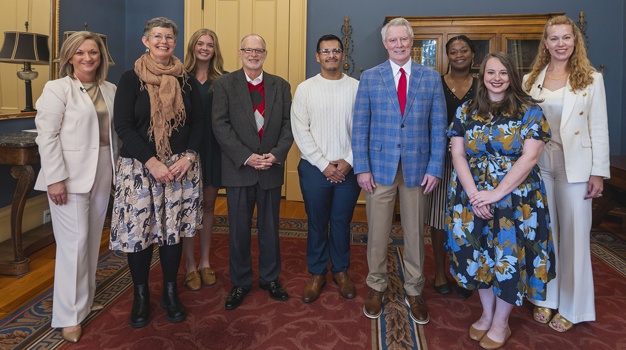 A group of people stand in a line in an ornate office.