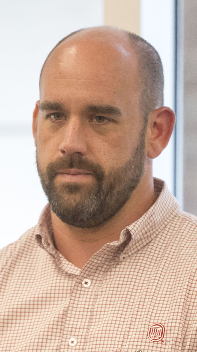 Headshot of a man wearing a checked dress shirt.