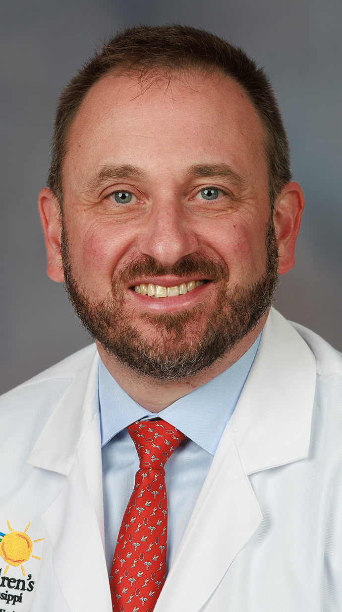 Headshot of a man wearing a doctor's white coat.