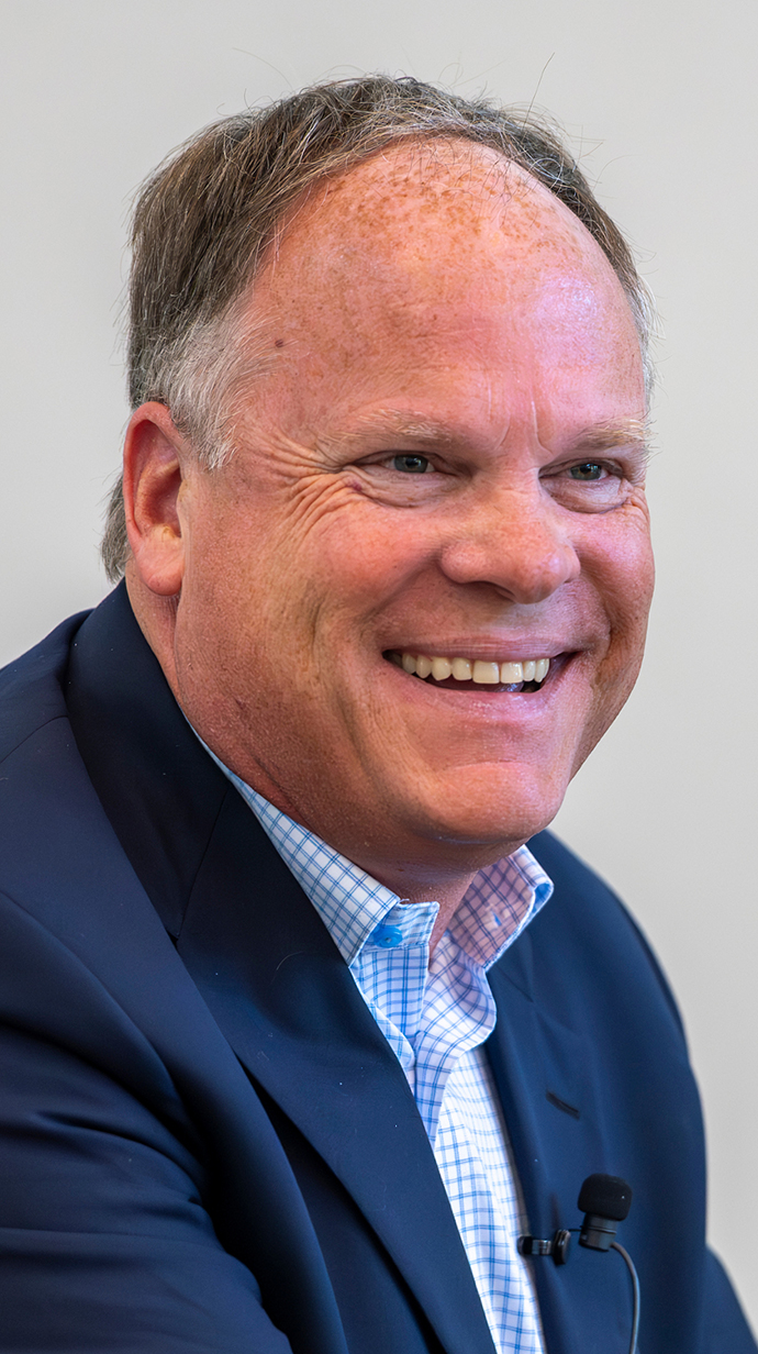 Headshot of a man wearing a blue suit with no tie.