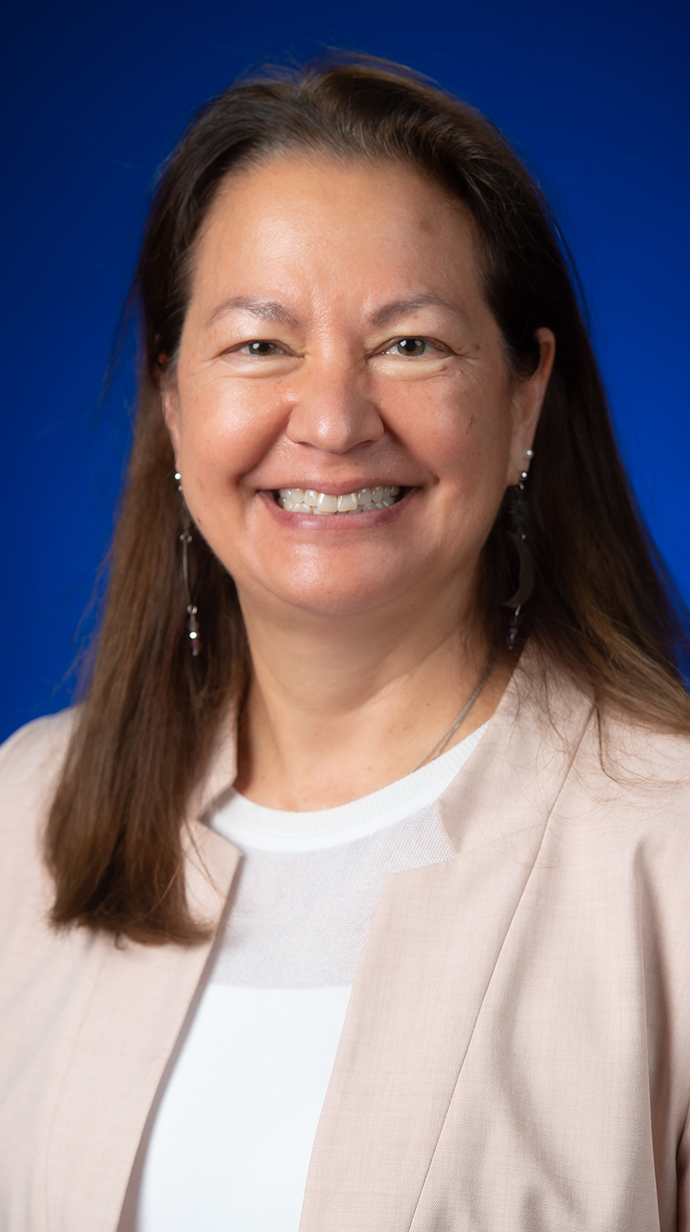 Headshot of a woman wearing a beige jacket over a white blouse.