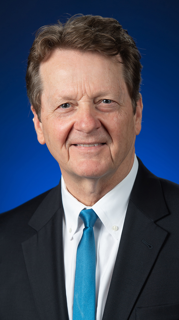 Headshot of a man wearing a dark suit with an aqua tie.