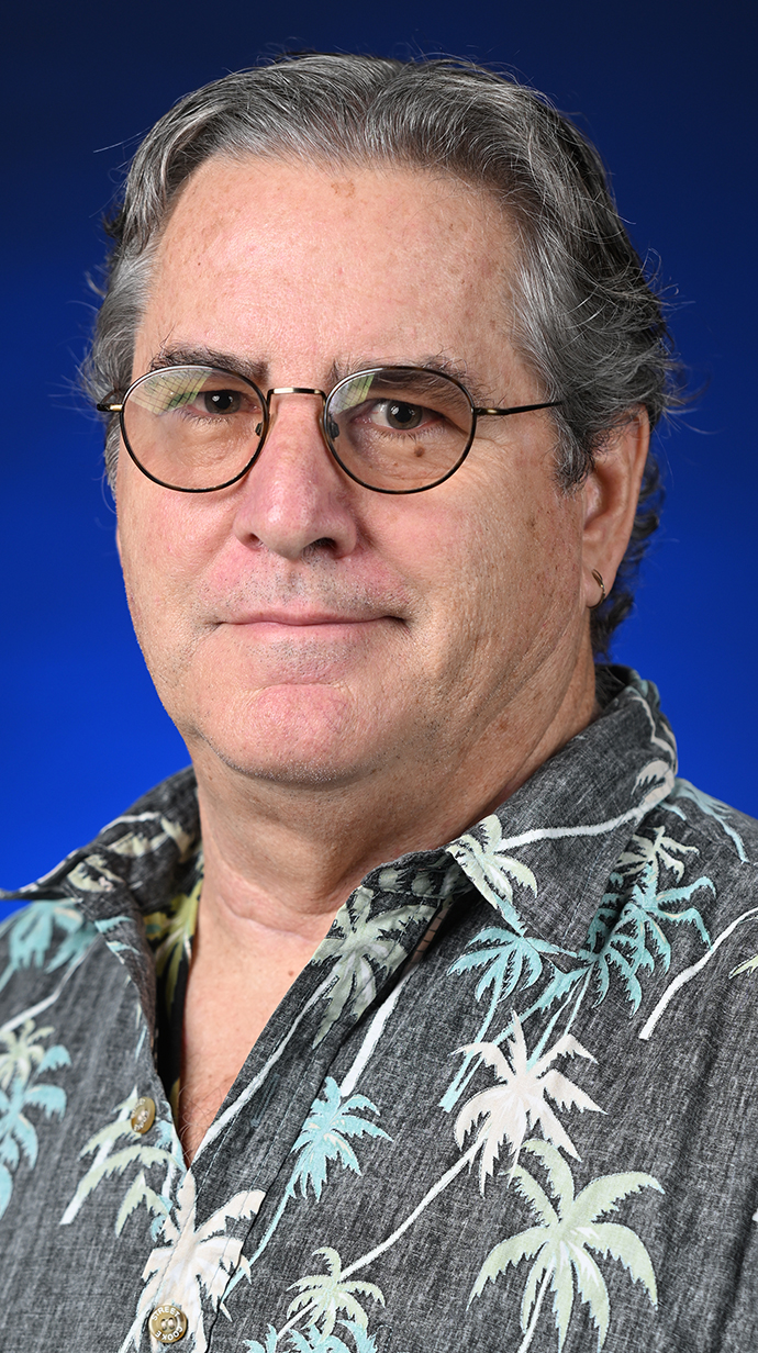 Headshot of a man wearing a gray Hawaiian shirt.