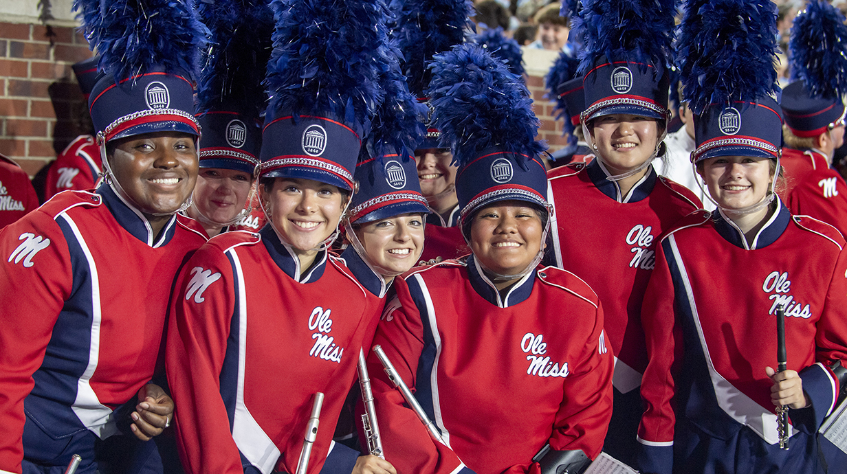 Several young people, all dressed in Ole Miss band uniforms, wait to march onto the field.