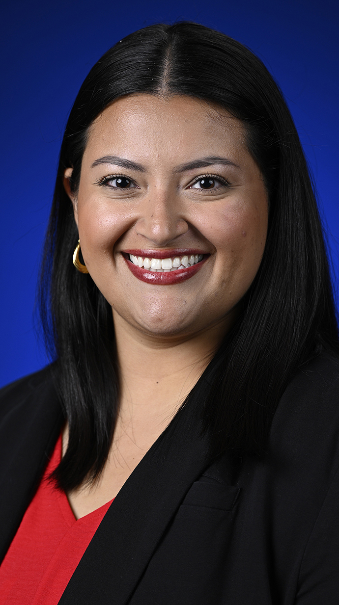 Headshot of a young woman wearing a black jacket over a red blouse.