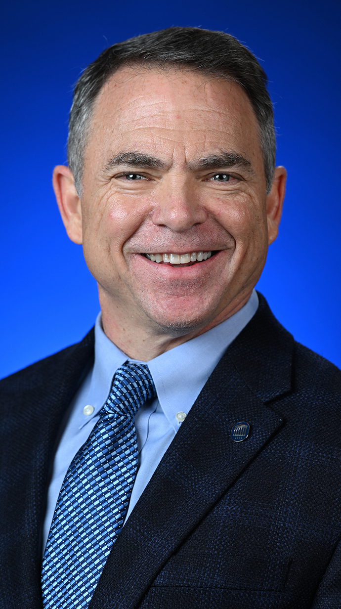 Headshot of a man wearing a dark blue suit.