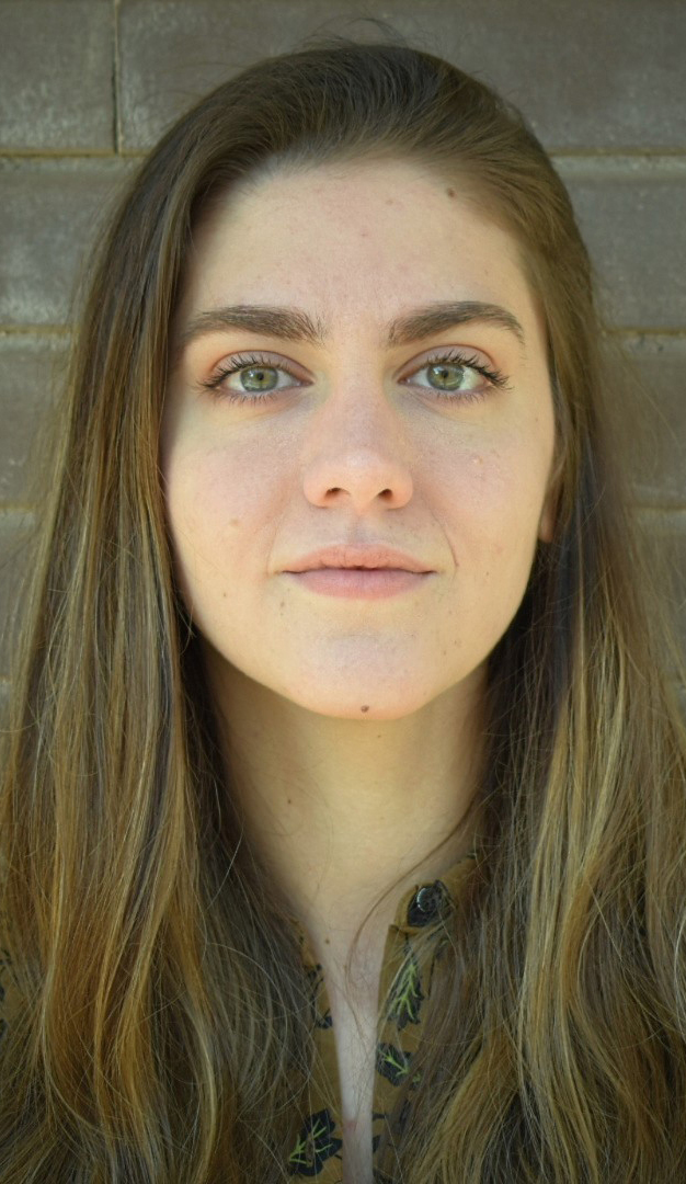 Headshot of a woman wearing agold shirt with a black leaf pattern.