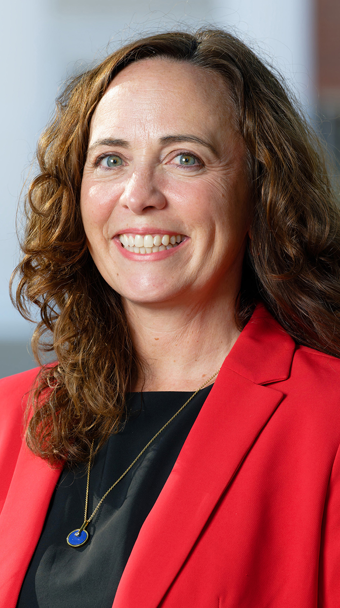 Headshot of a woman wearing a red jacket over a black blouse.