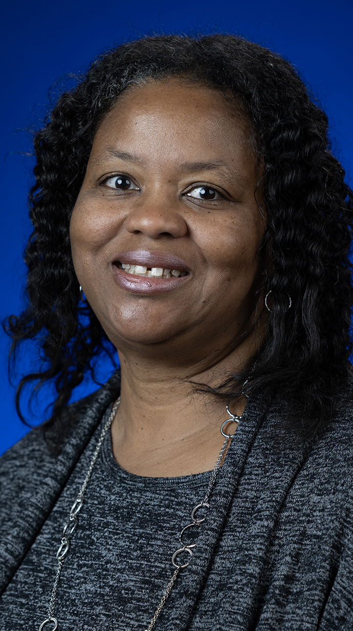 Headshot of a woman wearing a gray sweater and blouse.