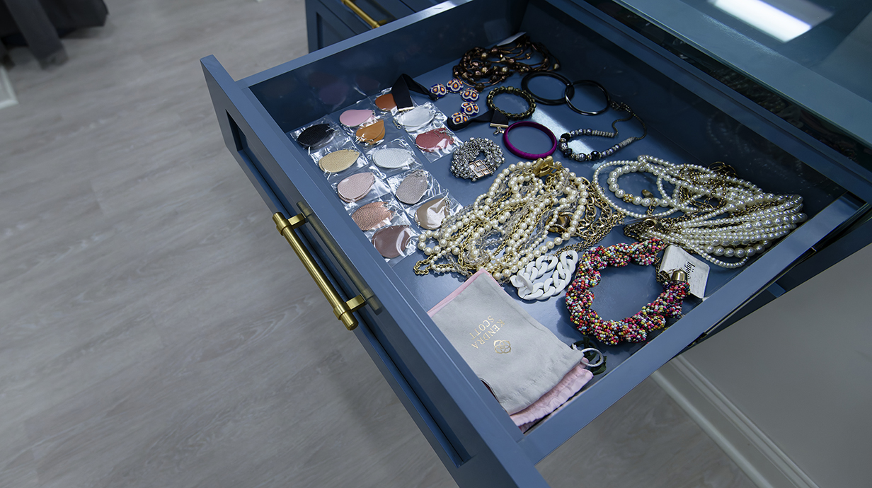 A drawer on a display case is lined with jewelry and other accessories.