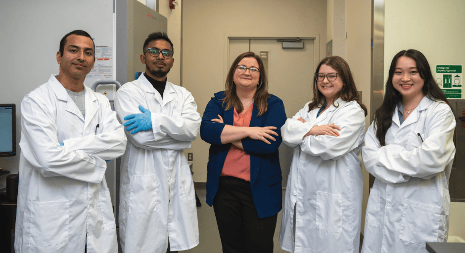 An image of Abigal Moeller and her research lab members with their arms crossed smiling at the camera.
