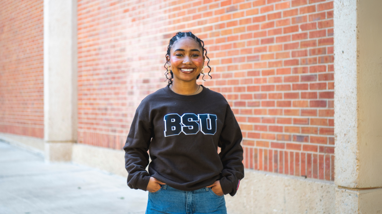 An image of Bre'Anna Coleman wearing a sweatshirt that says, "BSU" while posing in front of a brick wall.