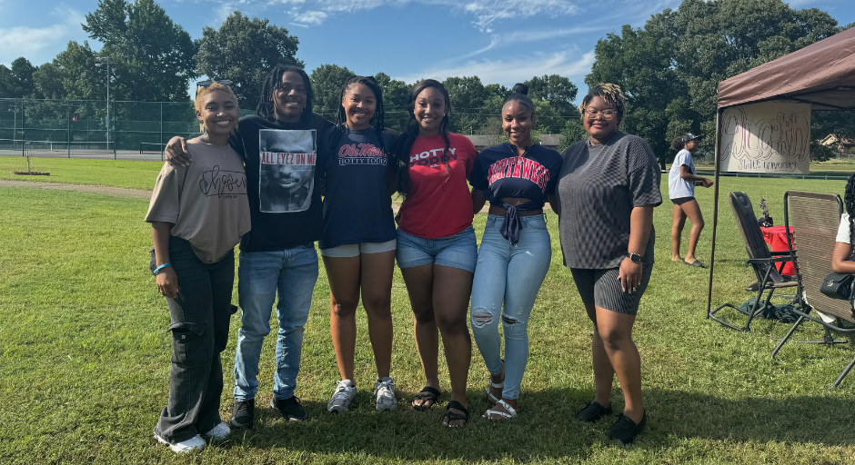 Bre'Anna Coleman (left) and five other people smiling at the camera while outside.
