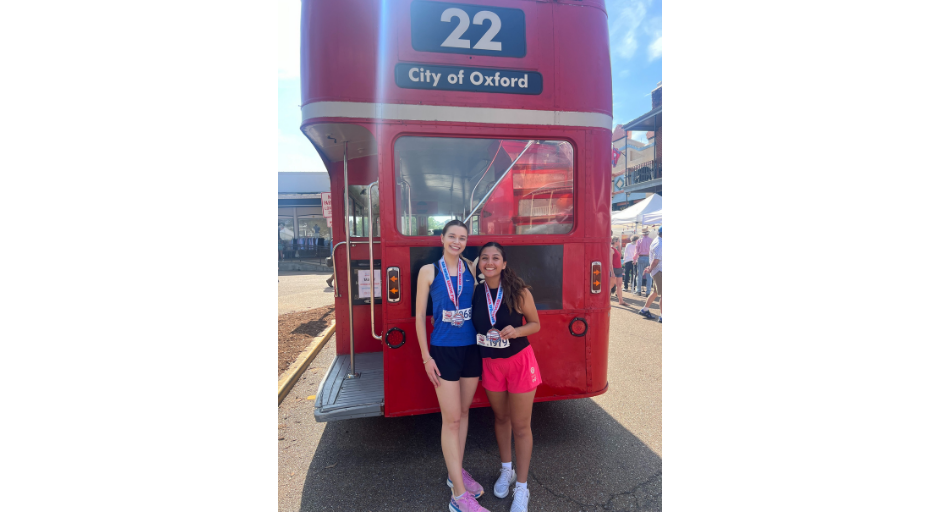 An image of Caroline McCutchen and Jackie La Riva in front of a red double decker bus. 