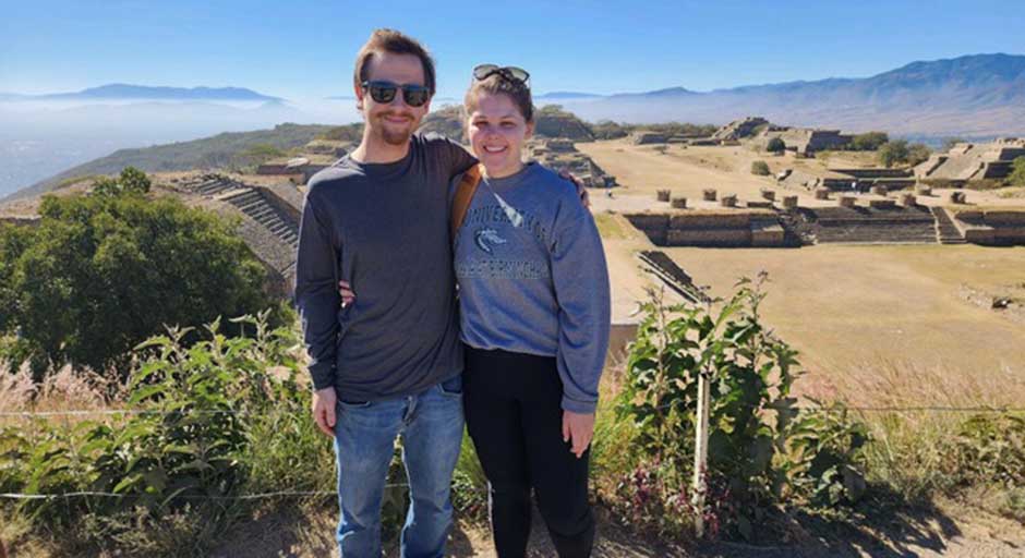 Couple stands in front of ancient ruins in Oaxaca, Mexico