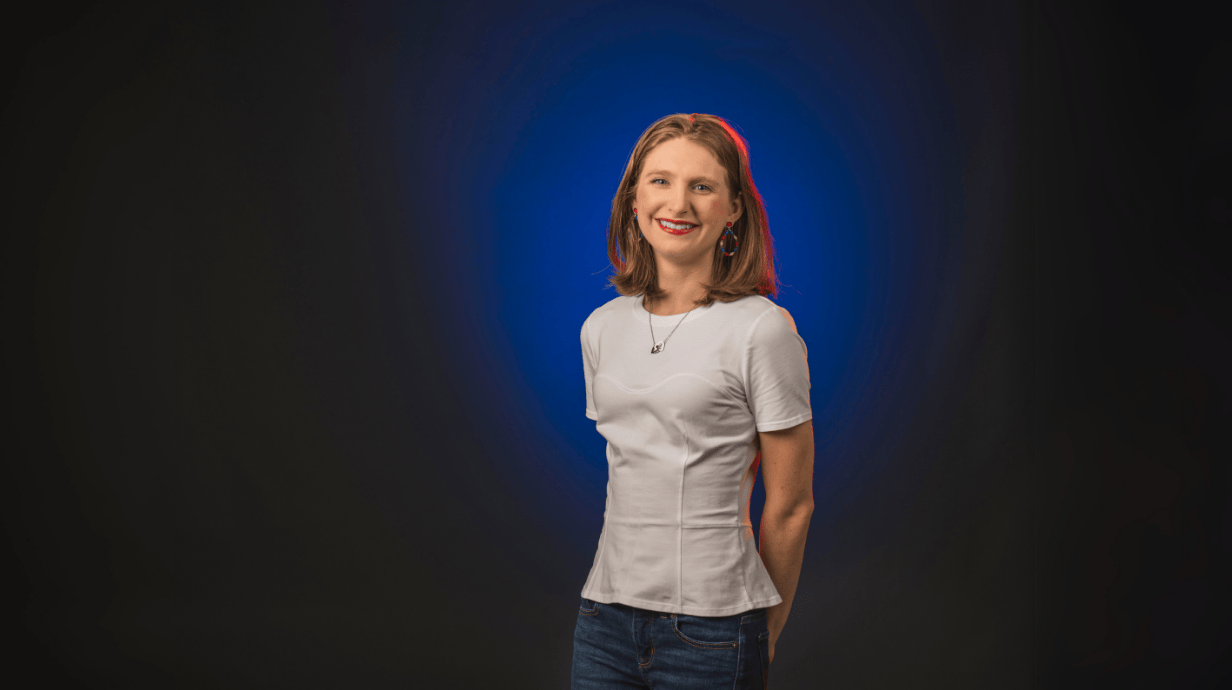 An image of Emma Delahoussaye in front of a blue backdrop.