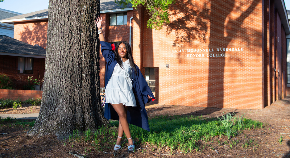 Janelle Minor posing in front of the Sally McDonell Barksdale Honors College.