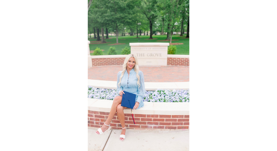 Lindsay Ashton holding her graduation cap while sitting in the new welcome area of the Grove.