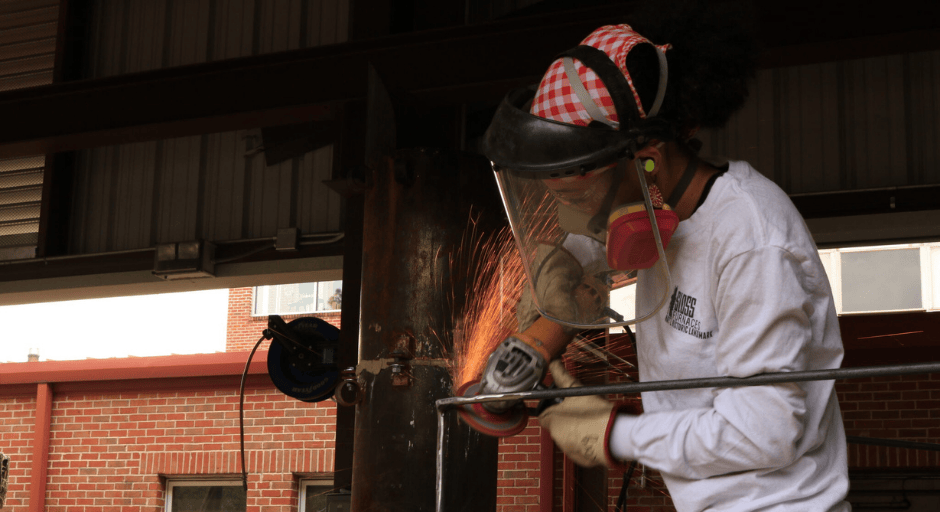 Rory Randle uses a power sander on her 11-foot steel house for her senior thesis.