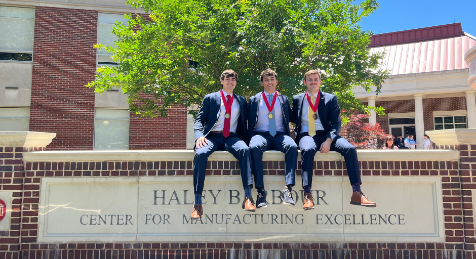An image of Shane Houston Stephens, Jack Reichle and Jon Floyd Dunn sitting atop the Haley Barbour Center for Manufacturing Excellence monument.