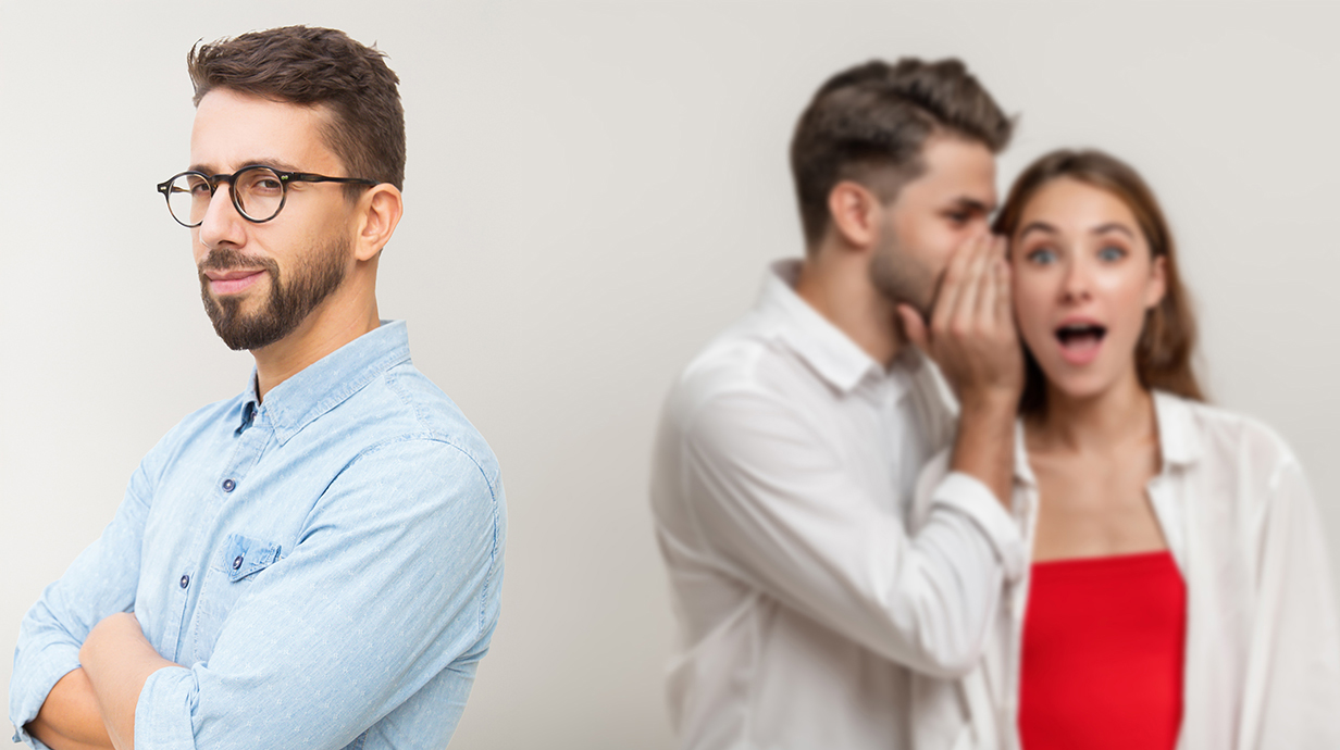 A man and a woman whisper as another man stands with his back to them.
