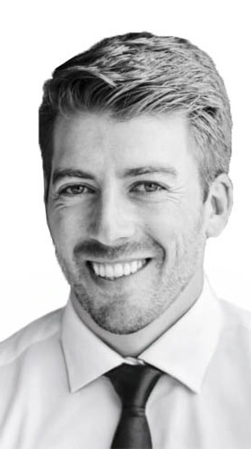 Black-and-white headshot of a man wearing a collared shirt and a dark necktie.