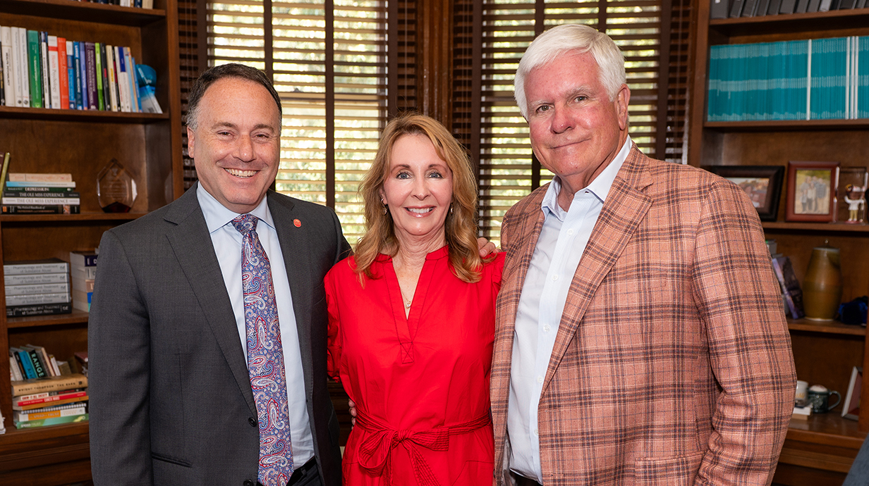 Two men and a woman stand in an office.