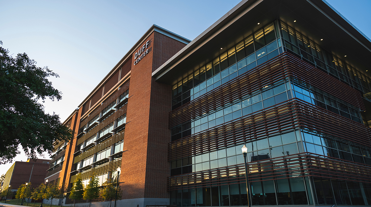 Facade of a large, modern building with large windows and metal louvers.