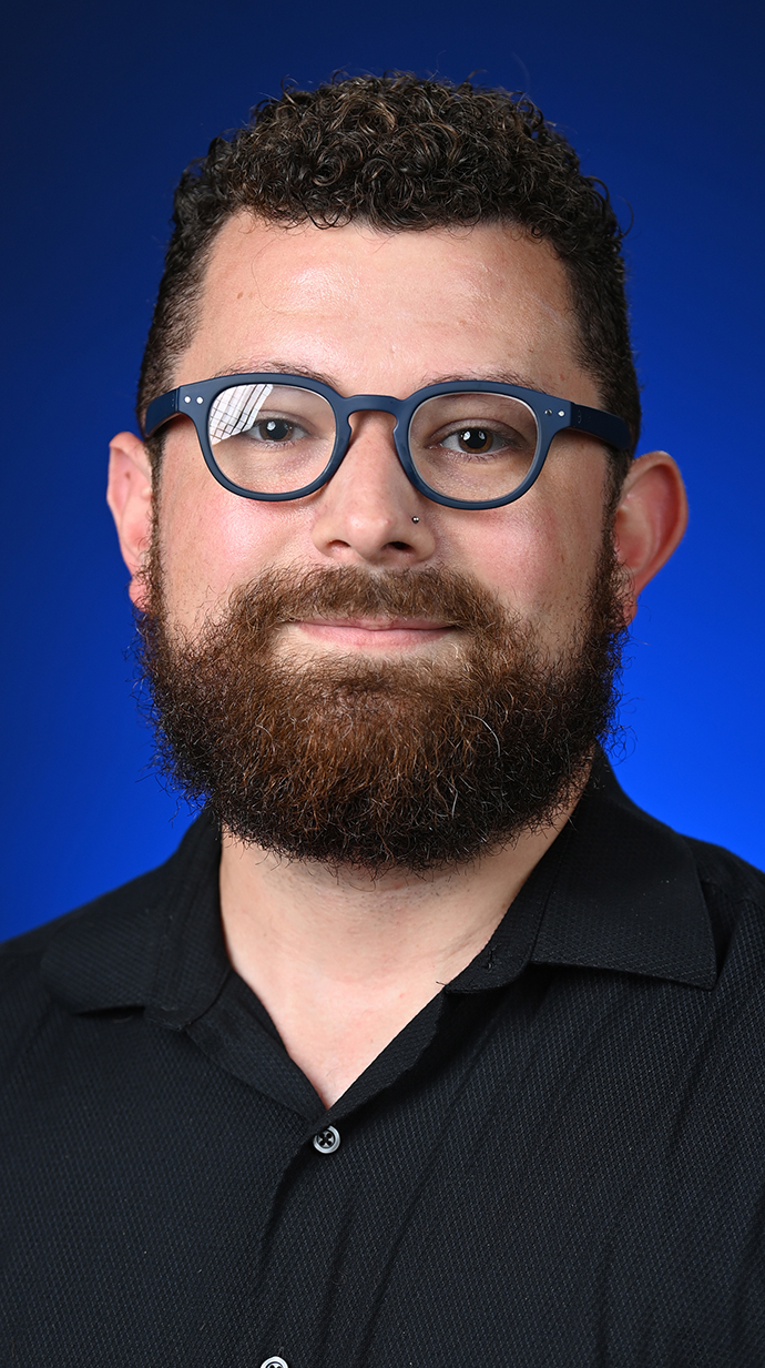 Headshot of a man wearing glasses and a black shirt.