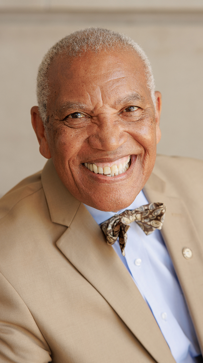 Headshot of a man wearing a tan suit.