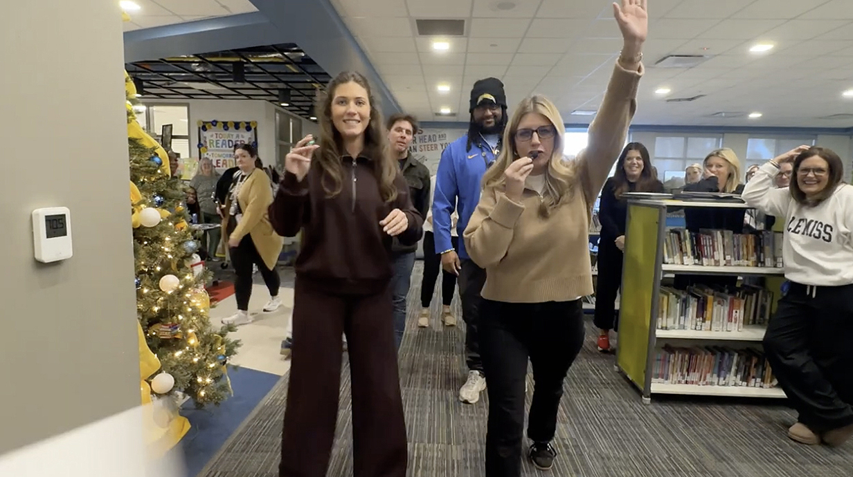 Several men and women look into a camera in a library.