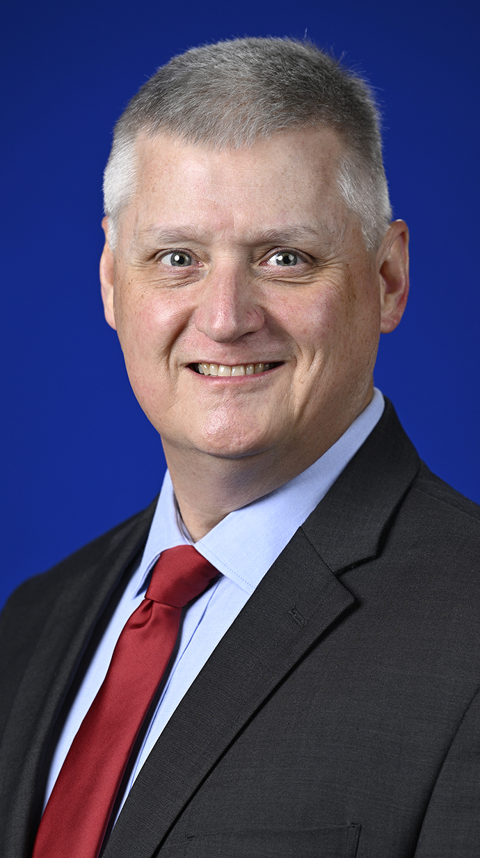 Headshot of a man wearing a dark suit with a red tie.