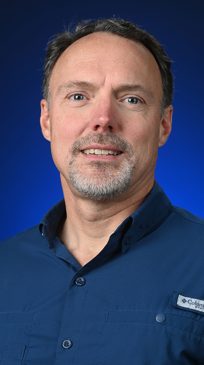 Headshot of a man wearing a blue-green shirt.