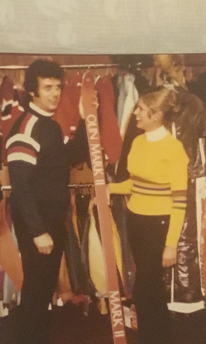 A young man and young woman examine ski equipment in a store.